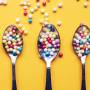 top_view_three_spoons_with_colorful_sprinkles_on_yellow_background.jpg